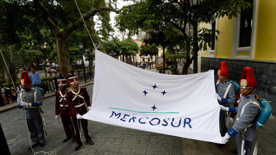 Izan la bandera del Mercado Común del Sur (Mercosur) frente a la Cancillería de Venezuela, en Caracas (capital), 5 de agosto de 2016.