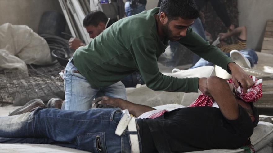 Un hombre cuida a un manifestante palestino que resultó herido en un enfrentamiento con militares israelíes.