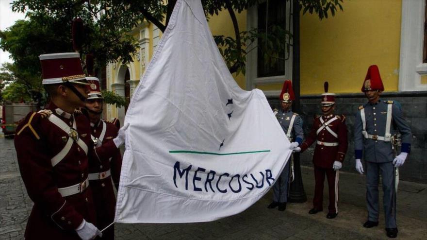 Izan la bandera del Mercado Común del Sur (Mercosur) frente a la Cancillería de Venezuela, en Caracas (capital), 5 de agosto de 2016.