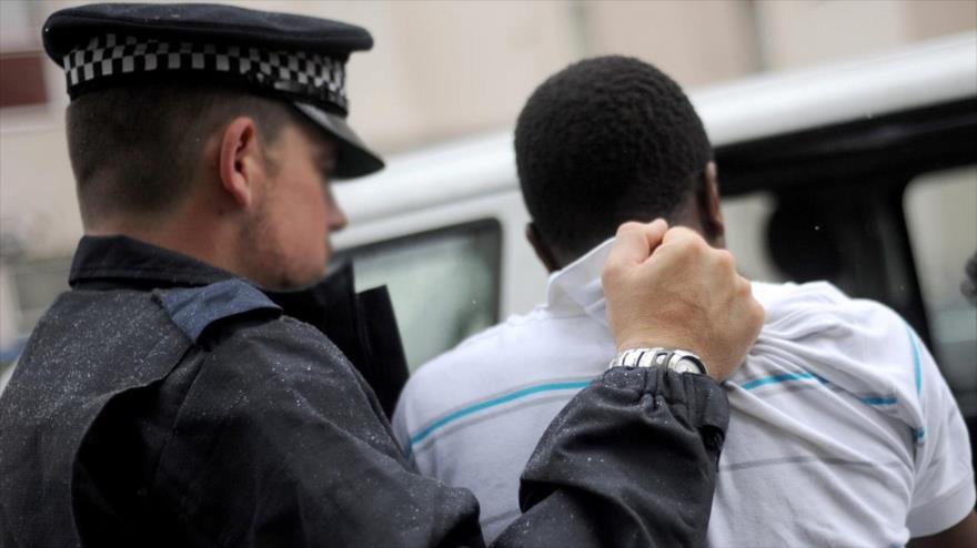 Un policía británico detiene a un negro.