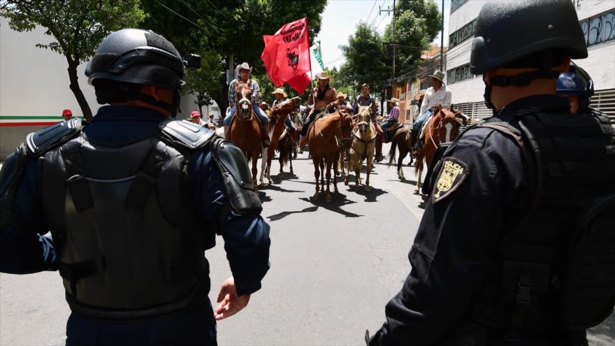 Policías mexicanos observan a miembros de la organización social Frente Popular Francisco Villa que salieron a las calles en apoyo a la Coordinadora Nacional de Trabajadores de la Educación (CNTE), 20 de julio de 2016.