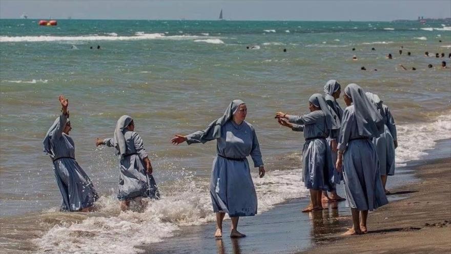 La foto que subió Izzedin Ezir en su Facebook, muestra unas monjas vestidas con sus hábitos que juegan en la playa.