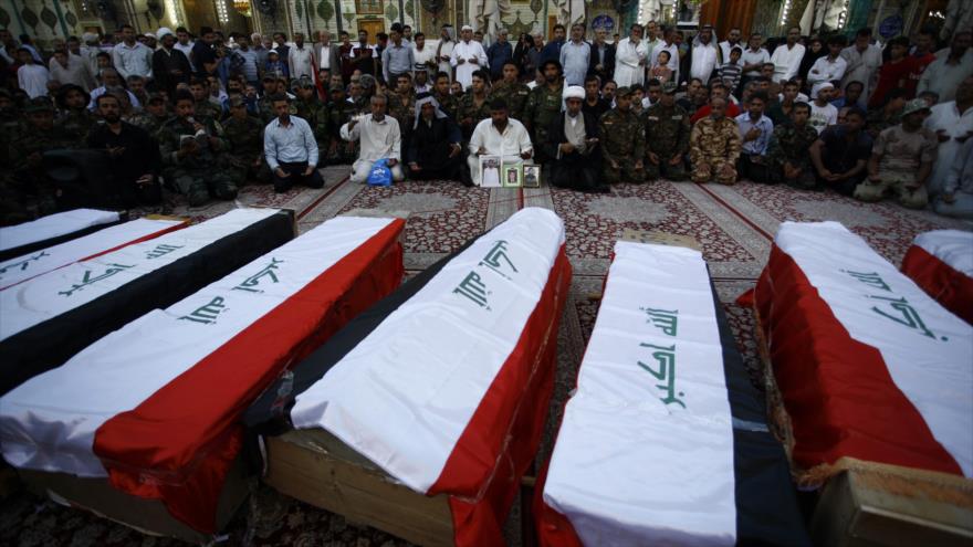 Civiles y soldados iraquíes lloran junto a los ataúdes que contienen los restos de diez de sus compañeros que fueron asesinados en la masacre Speicher, 1 de julio de 2015. 