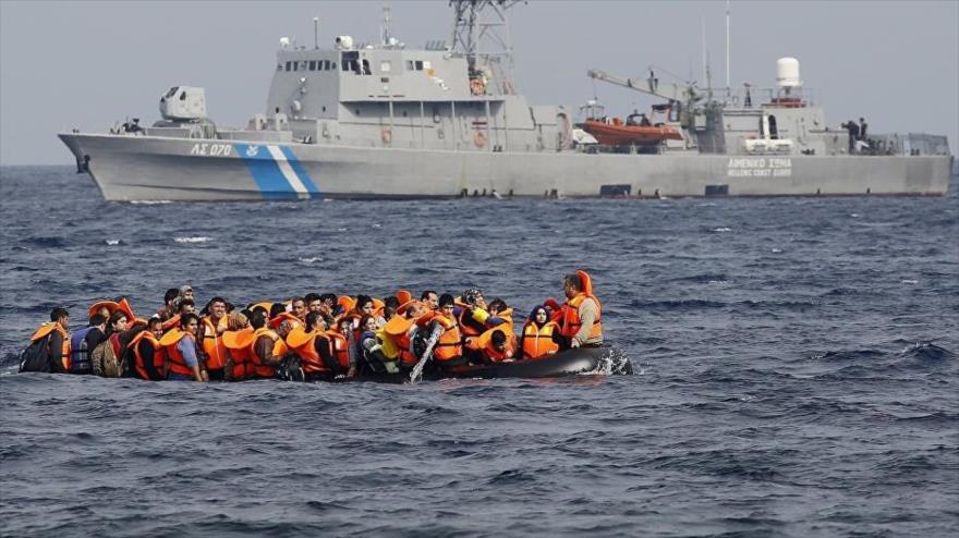 Un barco de refugiados pasa cerca de un buque de la Guardia Costera de Grecia.