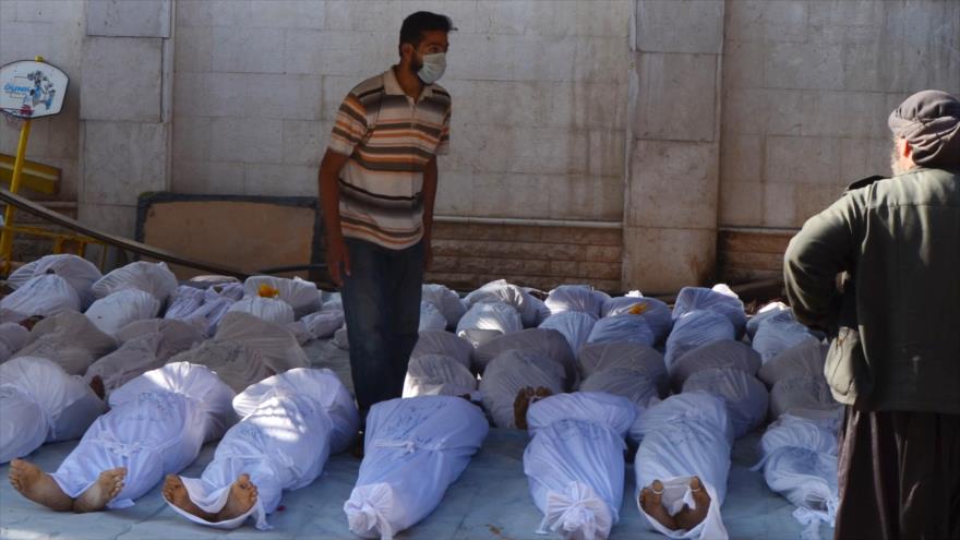 Un hombre inspecciona los cuerpos de personas que habían muerto en un ataque con gas nervioso en Quta Oriental, en 2013.