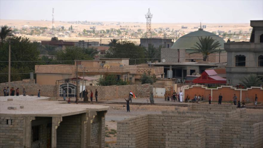 Un hombre sostiene una bandera nacional iraquí, mientras las fuerzas iraquíes toman una posición clave en la ciudad de Al-Qayarah, al sur de la importante ciudad de Mosul, al norte de Irak. 24 de agosto de 2016