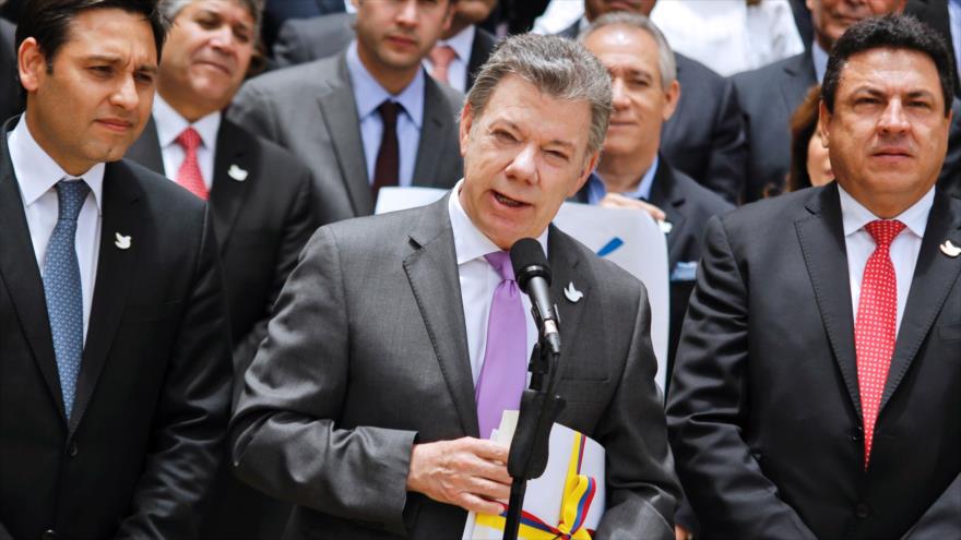 El presidente de Colombia, Juan Manuel Santos (C), lleva consigo la copia del texto final del acuerdo de paz alcanzado entre el Gobierno y las Fuerzas Armadas Revolucionarias de Colombia (FARC), que luego entregó al presidente del Congreso Nacional, Mauricio Lizcano (izqda.), en Bogotá, 25 de agosto de 2016.