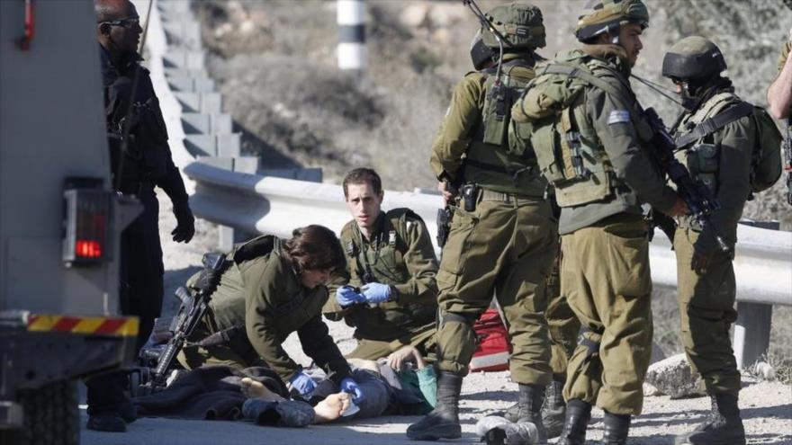 Soldados israelíes reunidos alrededor del cuerpo de un palestino muerto tras recibir disparos por tropas de este régimen en la ocupada Cisjordania.