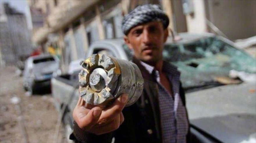 Un yemení muestra una bomba de racimo restante de un ataque aéreo de Arabia Saudí.