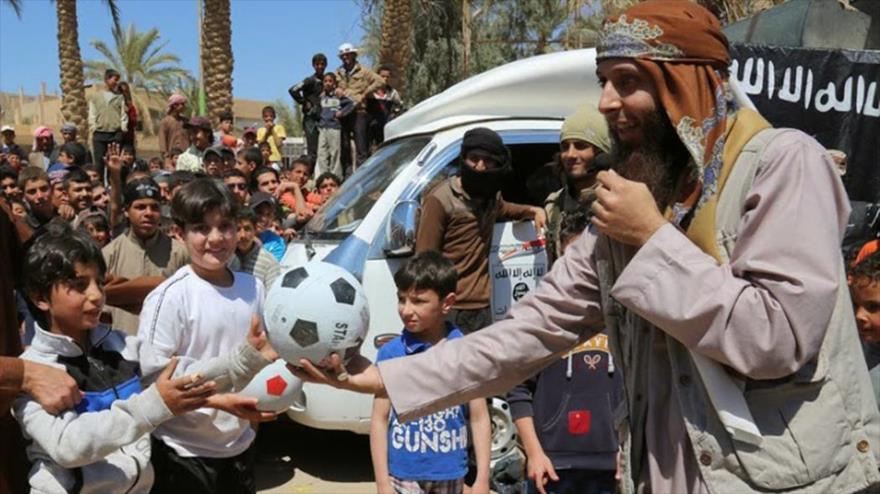 Un miembro del grupo terrorista takfirí EIIL (Daesh. en árabe) regala una bola de fútbol a un niño en Siria.