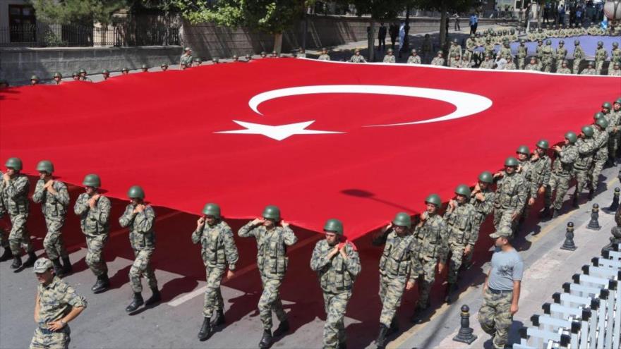 Militares turcos llevan una gran bandera nacional.