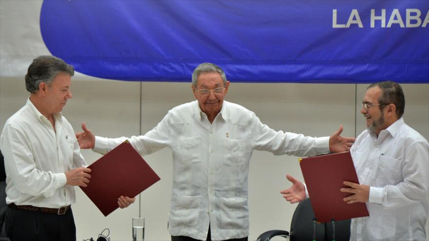El presidente de Colombia, Juan Manuel Santos (izda.) y el jefe máximo de las FARC, Timoleón Jiménez, (dcha.), junto con el presidente cubano, Raúl Castro (centro) durante la firma del alto el fuego en La Habana, el 23 de junio.