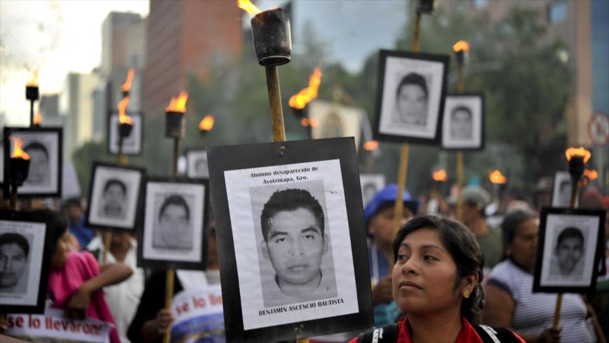 Los padres de 43 estudiantes desparecidos y maestros de Ayotzinapa sostienen retratos de los jóvenes y antorchas durante una marcha en la Ciudad de México, 26 de abril de 2016.