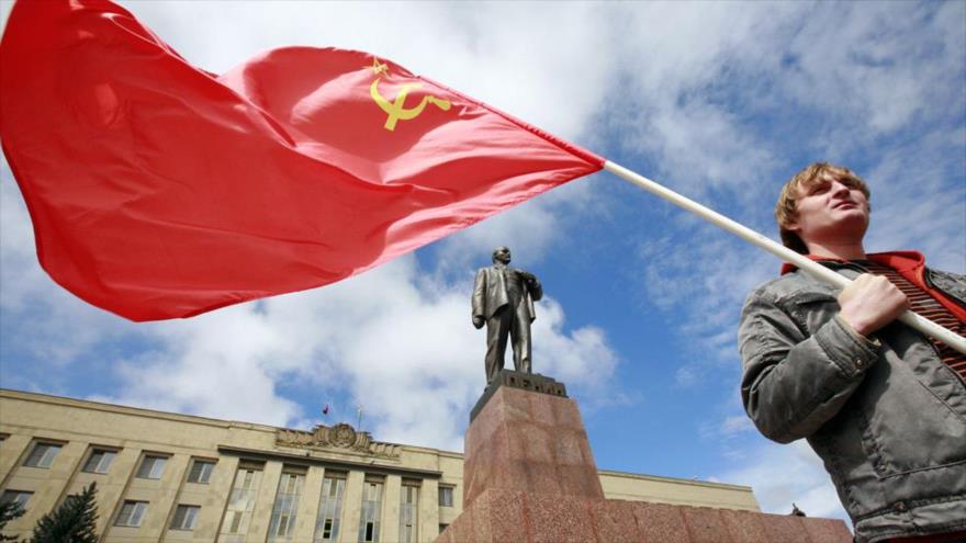 Un hombre sostiene la bandera roja de la antigua Unión Soviética delante de un monumento del líder bolchevique Lenin, en la ciudad de Stavropol (Rusia).