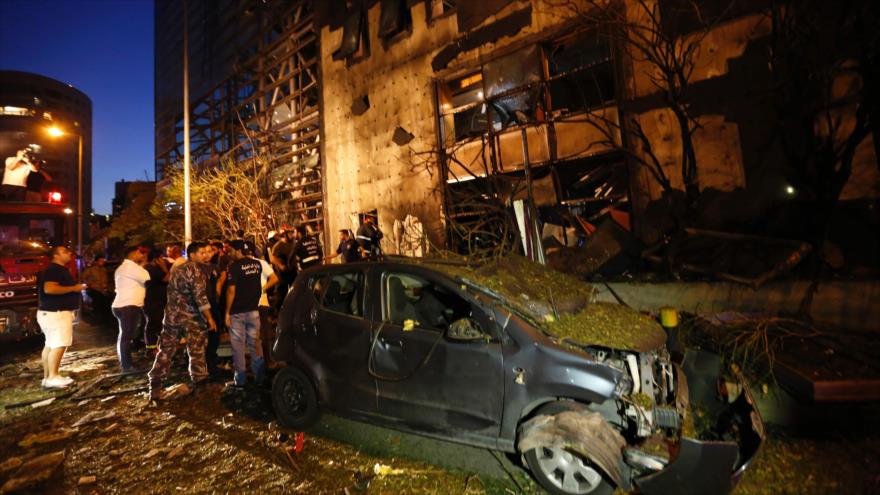 Los libaneses y los equipos del servicio de emergencia del país se congregan cerca de un vehículo destruido en un atentado terrorista en las cercanías de un conocido banco, en el oeste de Beirut, capital, 12 de junio de 2016.
