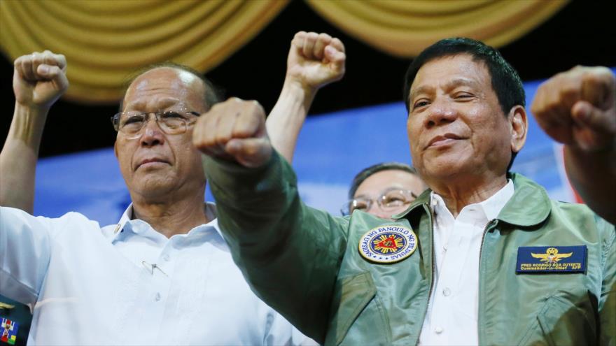 El presidente de Filipinas, Rodrigo Duterte (dcha.) posa con un puño con el ministro de Defensa, Delfin Lorenzana (izquierda), durante un acto.