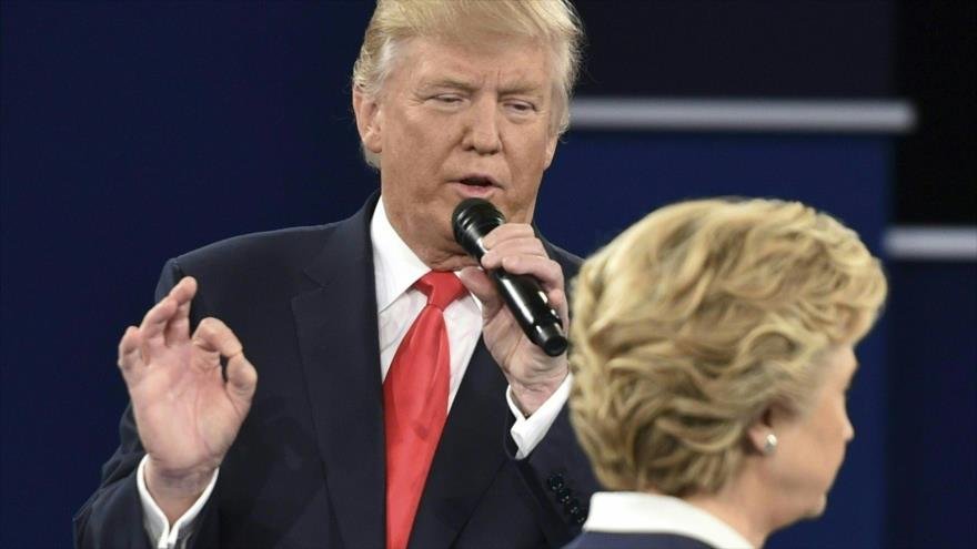 El candidato presidencial republicano Donald Trump habla, mientras la candidata demócrata Hillary Clinton pasa junto a él, en el segundo debate presidencial en la Universidad de Washington en St. Louis (Missouri, en Estados Unidos), 9 de octubre de 2016.