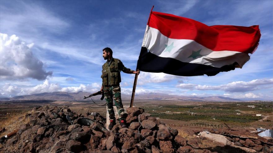 Soldado del Ejército sirio enarbola la bandera nacional sobre una colina en el distrito de Al-Lairamun (Alepo).