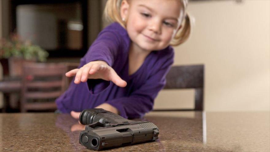 Una niña estadounidense se inclina para tomar una pistola.