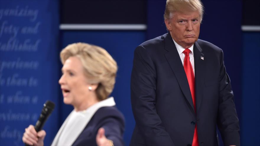 El republicano Donald Trump (dcha.) escucha a la demócrata Hillary Clinton durante el segundo debate presidencial, 9 de octubre de 2016.
