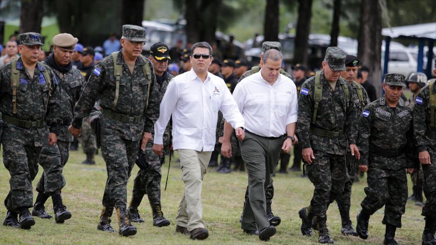 El presidente de Honduras, Juan Orlando Hernández (centro) acompañado con el secretario de Defensa, Samuel Reyes (a su dcha.), preside celebración del 52 aniversario del Segundo Batallón de Infantería Aerotransportado del país, 22 de agosto de 2016.