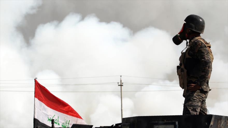 Un soldado del Ejército iraquí lleva máscara de protección contra los gases tóxicos liberados de una planta de azufre, incendiada por los terroristas de Daesh cerca de Mosul, norte de Irak, 22 de octubre de 2016.