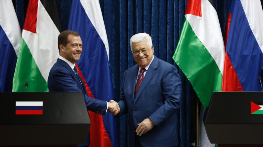 El primer ministro de Rusia, Dmitri Medvedev (izda.), estrecha la mano del presidente palestino, Mahmud Abás, tras ofrecer una rueda de prensa conjunta en la ocupada Cisjordania, 11 de noviembre de 2016.
