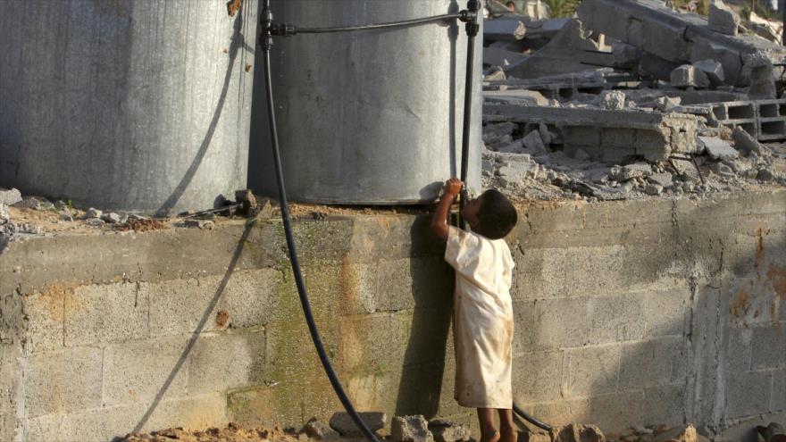 Un niño gazatí bebe agua de un depósito en el enclave costero palestino.