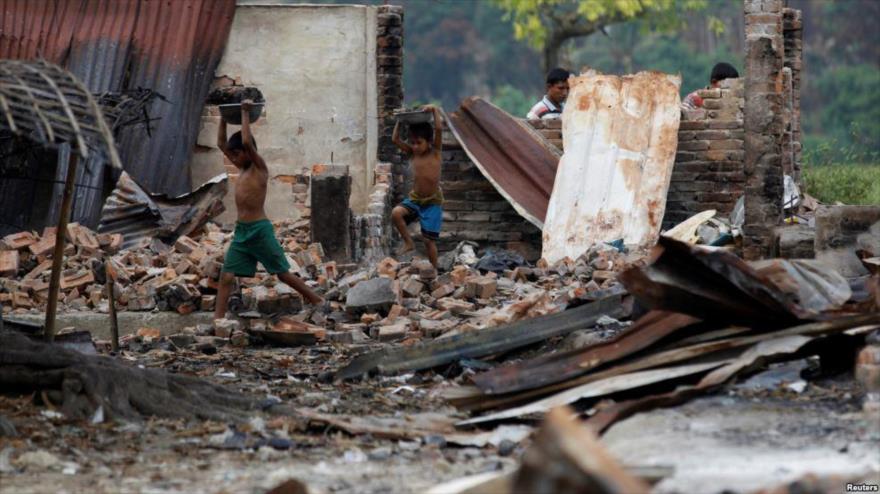 Los niños recogen materiales de las ruinas de un mercado que fue incendiado en una aldea de Rohingya, en las afueras de Maugndaw, en el estado de Rajine, Myanmar, 27 de octubre de 2016.
