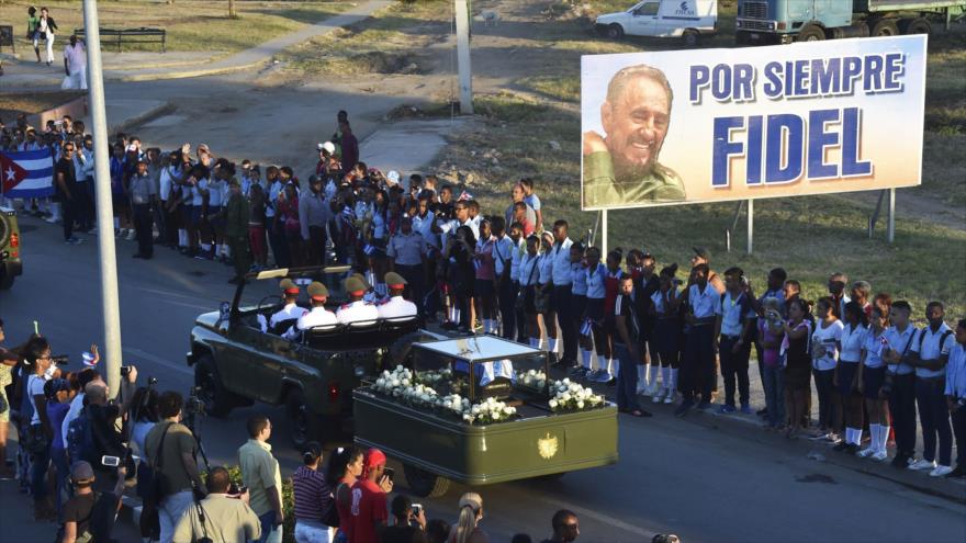 Los cubanos asisten al paso de la urna con las cenizas del líder cubano Fidel Castro desde la Plaza de la Revolución en Santiago de Cuba en su camino hacia el cementerio, 4 de diciembre de 2016. 