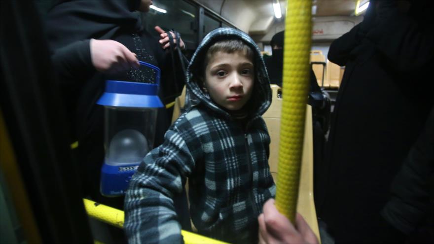 Un niño sirio se para en un autobús para moverse a una zona bajo control del Gobierno de Siria, 7 de diciembre de 2016.