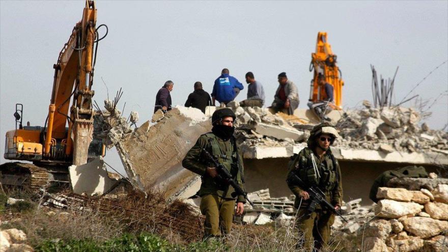 Soldados del régimen israelí montan guardia durante la demolición de una casa palestina en la ocupada Cisjordania, 21 de enero de 2016.