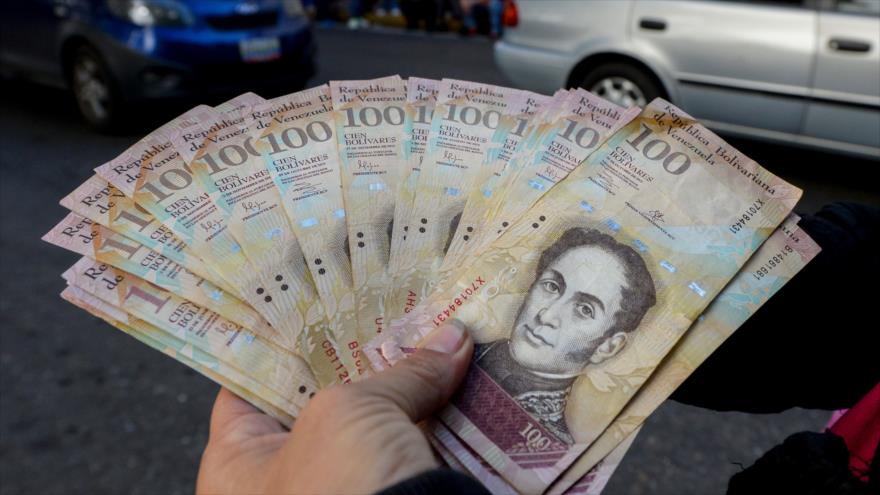 Un hombre lleva unos billetes de 100 bolívares frente al Banco Central de Venezuela (BCV), en un intento de cambiarlos, en Caracas, 16 de diciembre de 2016.