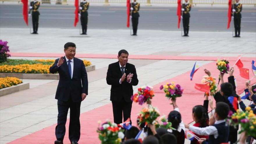 El presidente chino, Xi Jinping (izda.), y su par filipino, Rodrigo Duterte, son recibidos por estudiantes chinos a su llegada al Gran Salón del Pueblo en Pekín, capital china, 20 de octubre de 2016.