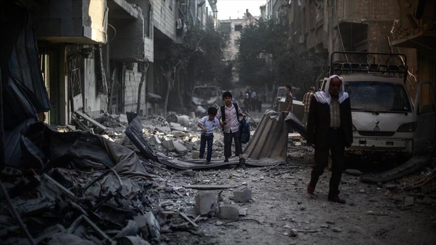 Dos niños de la ciudad siria de Alepo inspeccionan entre los escombros de los edificios destruidos en conflictos armados, septiembre de 2015.