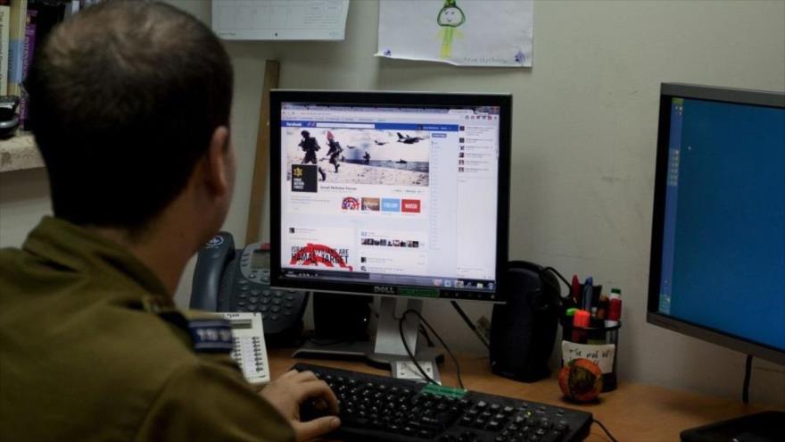 Un integrante del ejército del régimen de Tel Aviv revisando una cuenta de la red social Facebook.