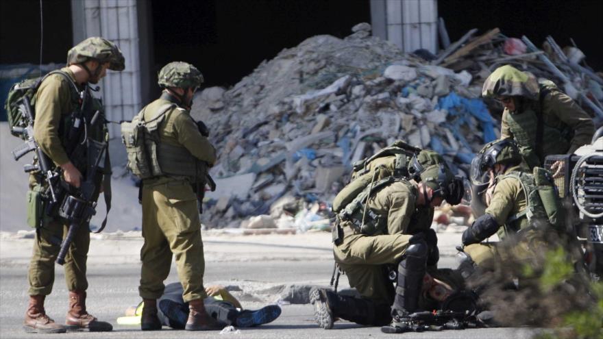 El cuerpo de un palestino que murió en un choque con un soldado israelí yace en el suelo.