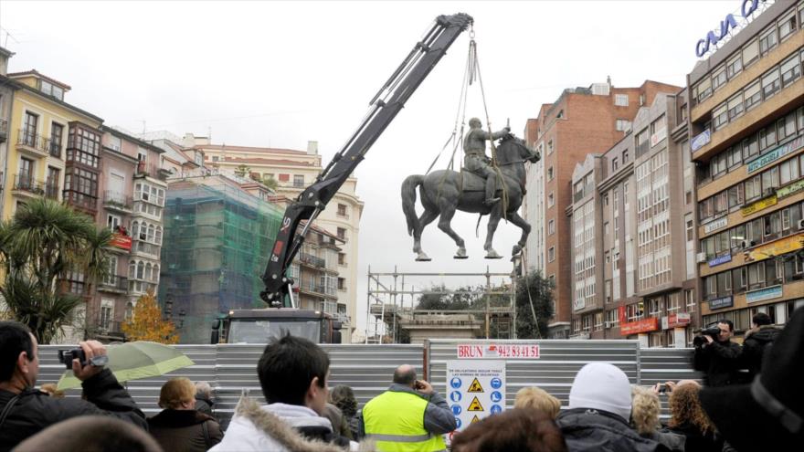 Ciudadanos españoles contemplan como se retira una estatua ecuestre del Francisco Franco en Santander, norte de España.