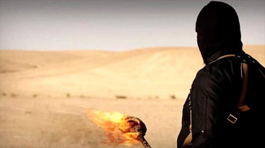Un terrorista del grupo EIIL (Daesh, en árabe lleva una antorcha en un desierto.