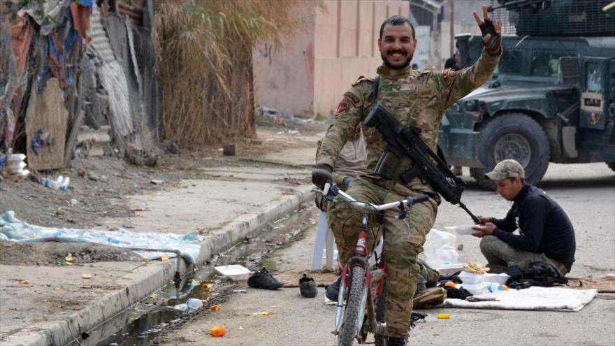 Un militar iraquíes hace el signo de la victoria mientras monta una bicicleta en una zona liberada en el sur de Mosul (norte de Irak), 13 de enero de 2017.