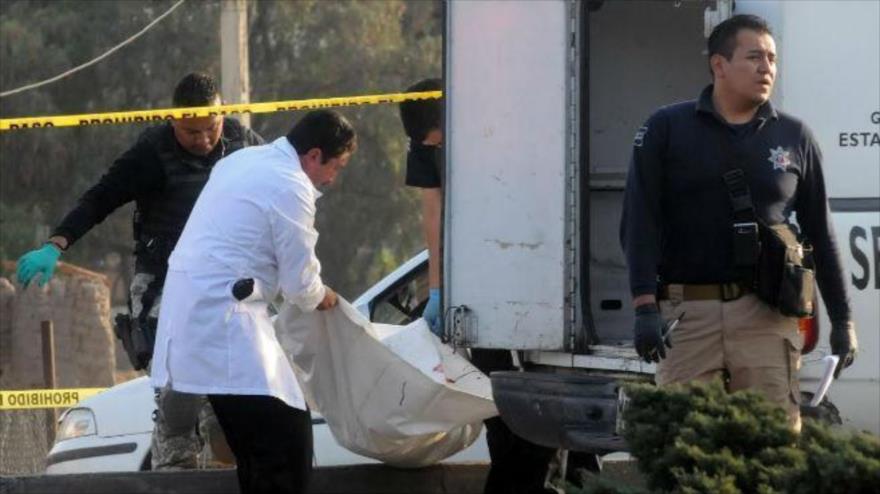Agentes de la Policía mexicana trasladan el cadáver de un hombre asesinado en el estado de Colima.