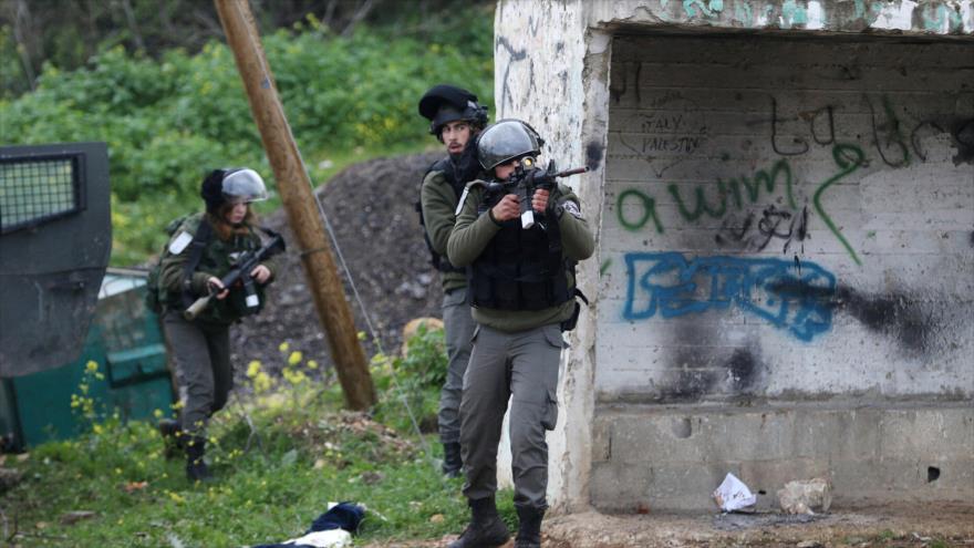 Un policía fronterizo israelí dispara contra un grupo de palestinos en la aldea cisjordana de Nabi Saleh, cerca de Ramalá, 3 de marzo de 2017. 