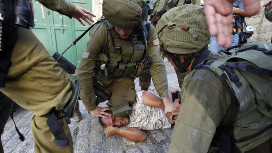Un soldado israelí mantiene con la rodilla la cabeza de un joven palestino pegada al suelo en la ciudad cisjordana de Al-Jalil (Hebrón), 20 de septiembre de 2016.