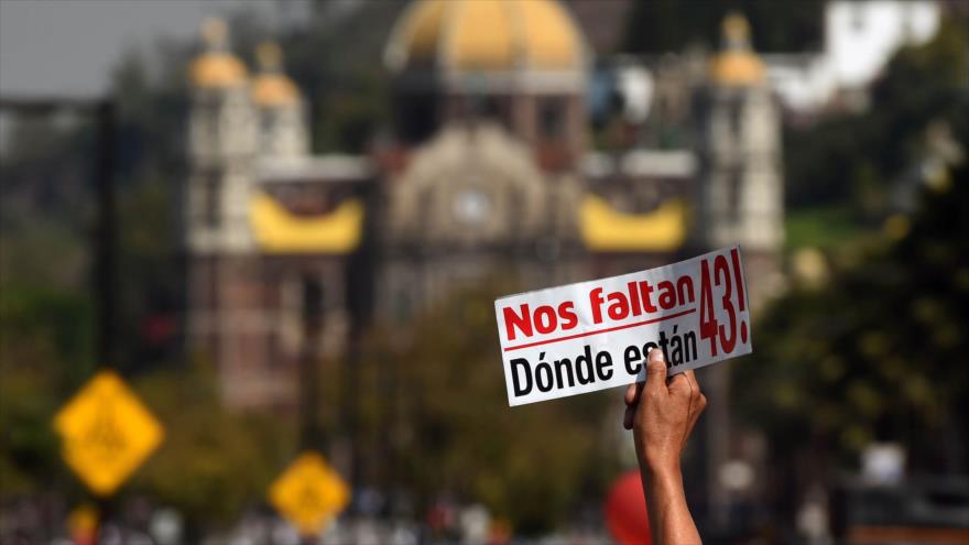 Una persona marchando con familiares y amigos de los 43 estudiantes de la Escuela Normal Rural Raúl Isidro Burgos de Ayotzinapa, en Guerrero, México, lleva una pegatina que dice "43 faltan ¿Dónde están?", 26 de diciembre de 2016.