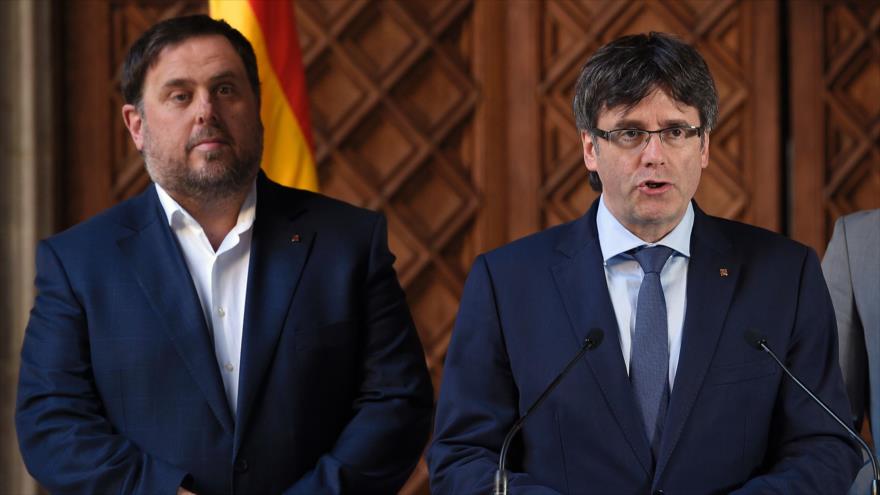 El presidente de la Generalitat, Carles Puigdemont (izda.), lee un comunicado oficial, flanqueado por su vicepresidente, Oriol Junqueras, 13 de marzo de 2017.