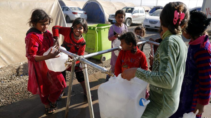 Niñas desplazadas iraquíes llenan sus contenedores de agua en el campo de refugiados Al-Khazar, cerca de Mosul (norte de Irak), 28 de noviembre de 2016.