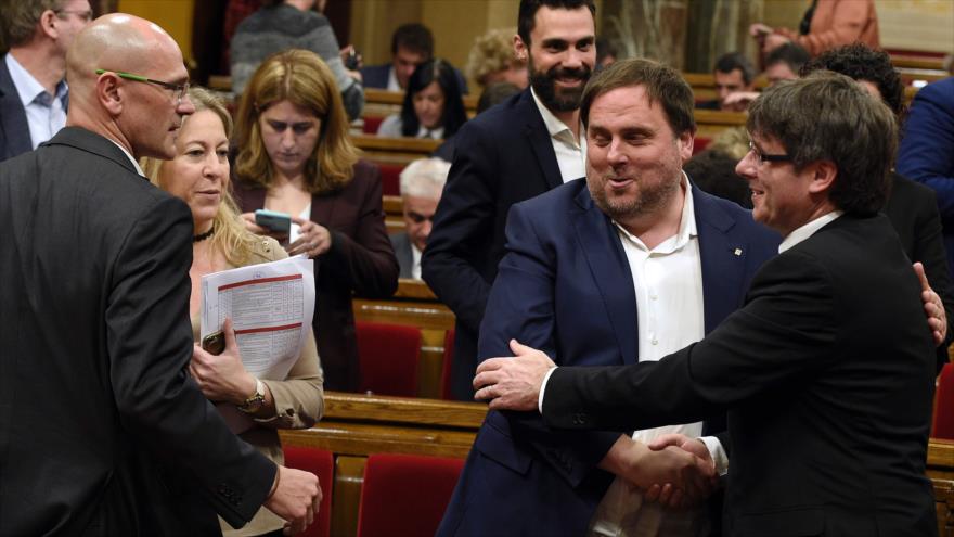 El presidente de la Generalitat, Carles Puigdemont (decha.) da la mano a su número dos, Oriol Junqueras, tras la aprobación de los Presupuestos de la Generalitat 2017, Barcelona, 22 de marzo de 2017.