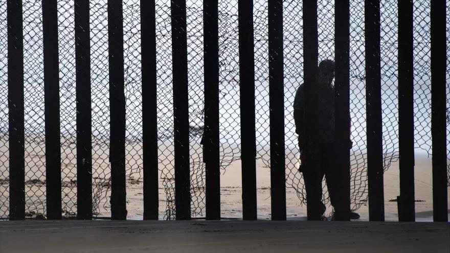 Un hombre se coloca en el lado de México de una valla fronteriza que separa al país azteca de Estados Unidos, 13 de febrero de 2017.