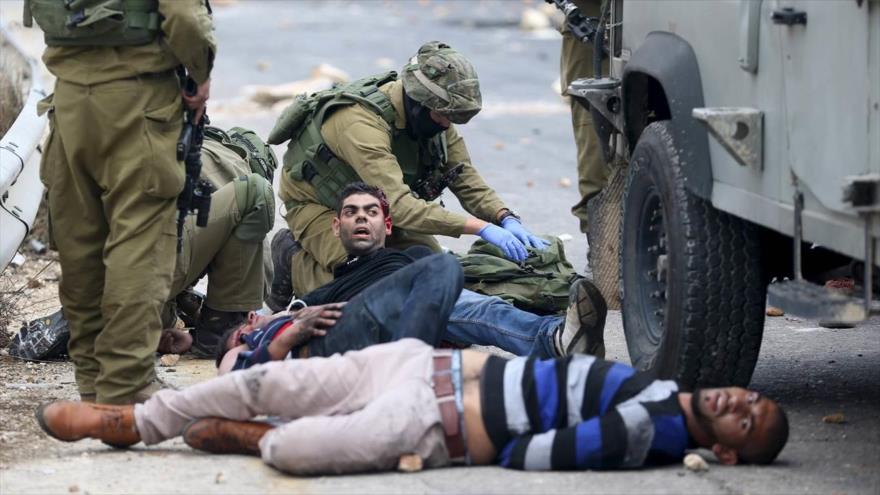 Soldados israelíes detienen a manifestantes palestinos heridos durante enfrentamientos registrados cerca del asentamiento ilegal de Bet El, que se encuentra cerca de la ciudad cisjordana de Ramalá, 15 de octubre de 2015.
