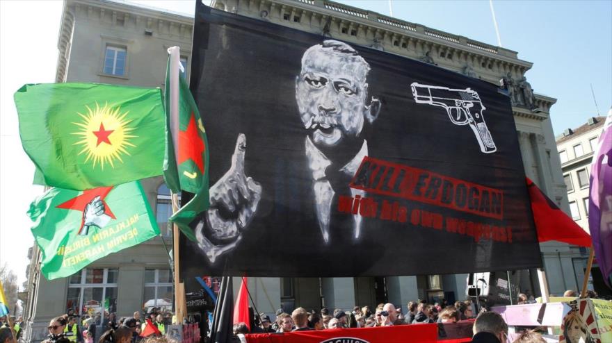 Los manifestantes en la ciudad suiza de Berna portan una pancarta en la que se puede ver al presidente turco, Recep Tayyip Erdogan, apuntado por una pistola, 25 de marzo de 2017.